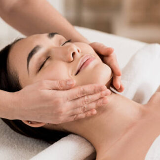 woman getting face massage with closed eyes at spa